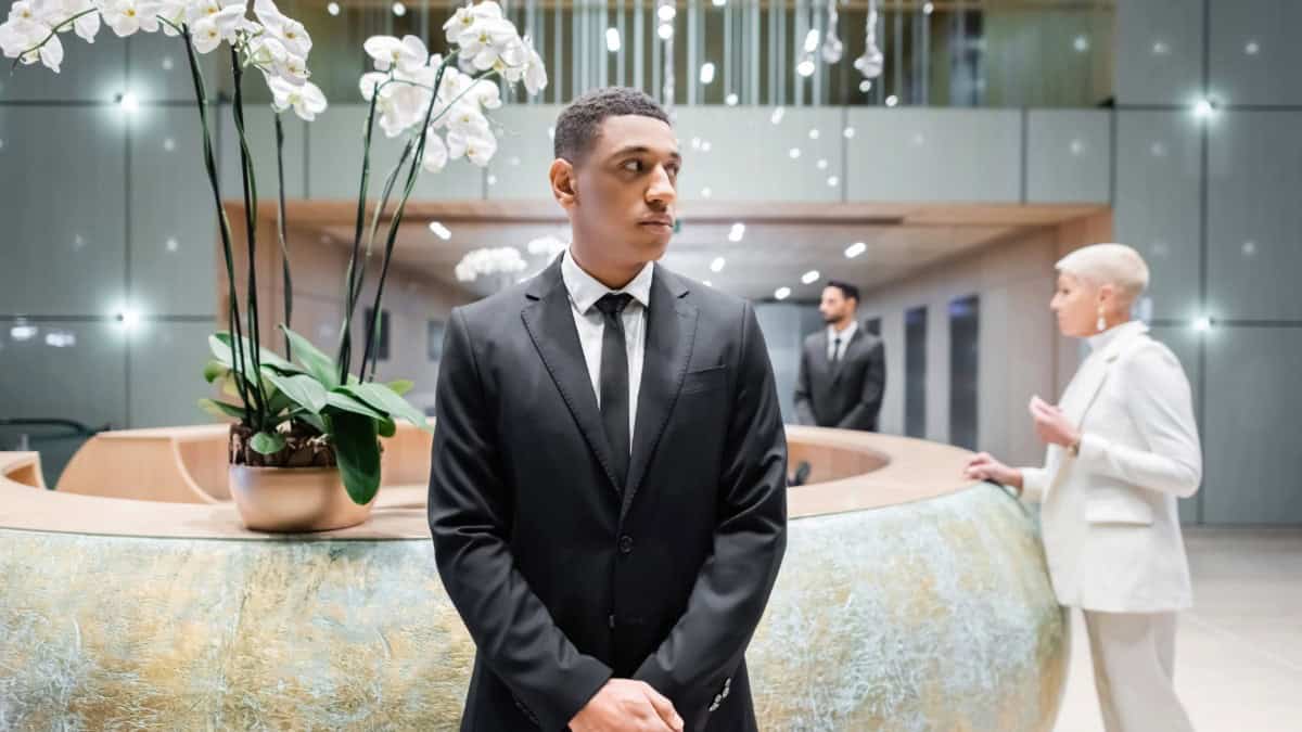 Security guard in formal attire standing in a modern office lobby for Freeman Protective Services.