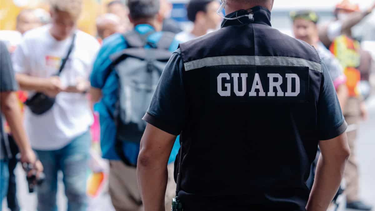 Security guard in uniform overseeing a crowd at a public event.